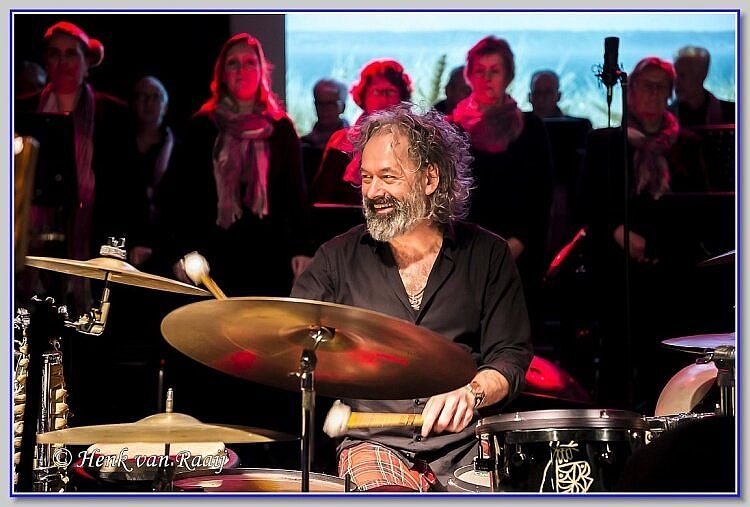Jan Wolfkamp breed lachend achter zijn drumstel, spelend tijdens de Bende van Beuving.
